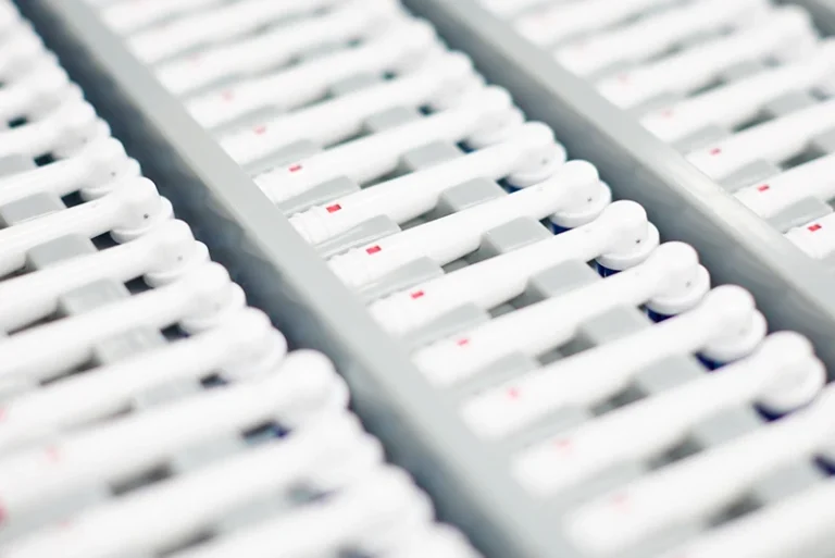 Rows of white electric toothbrush components arranged in trays.