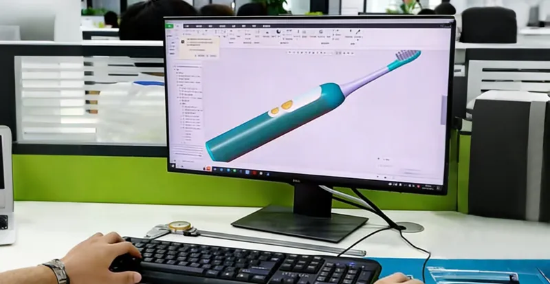 An R&D engineer working on 3D CAD modeling for a new electric toothbrush design on a computer monitor.