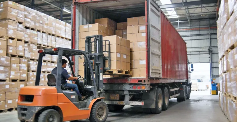 Forklift loading a shipping container with stock boxes of oral care products for swift global dispatch.