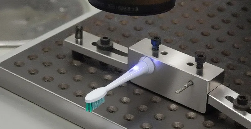 Precision laser marking machine applying a custom brand logo onto a ready-to-brand electric toothbrush for turnkey private labeling.